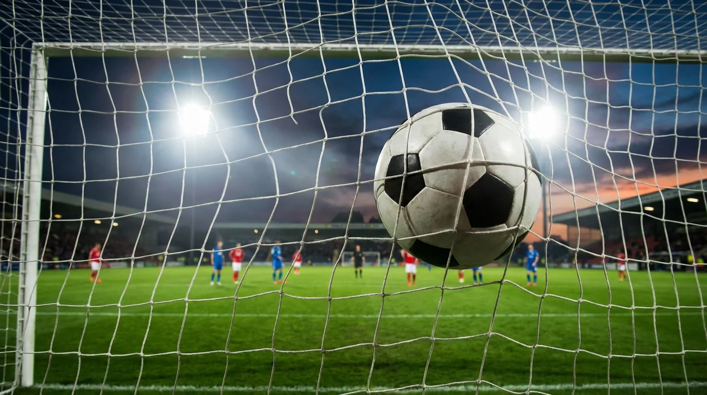 Rete di un campo da calcio con il pallone che entra in porta durante una partita